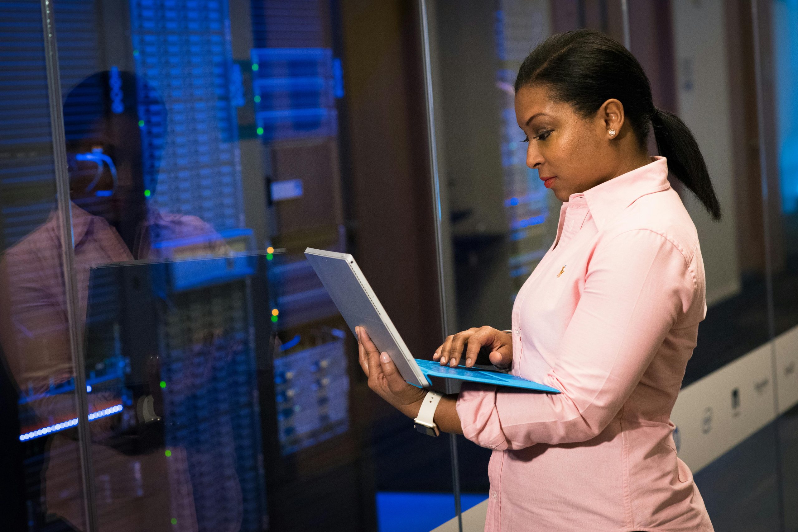 A focused software engineer working on a laptop in a server room, reflecting dedication in tech.