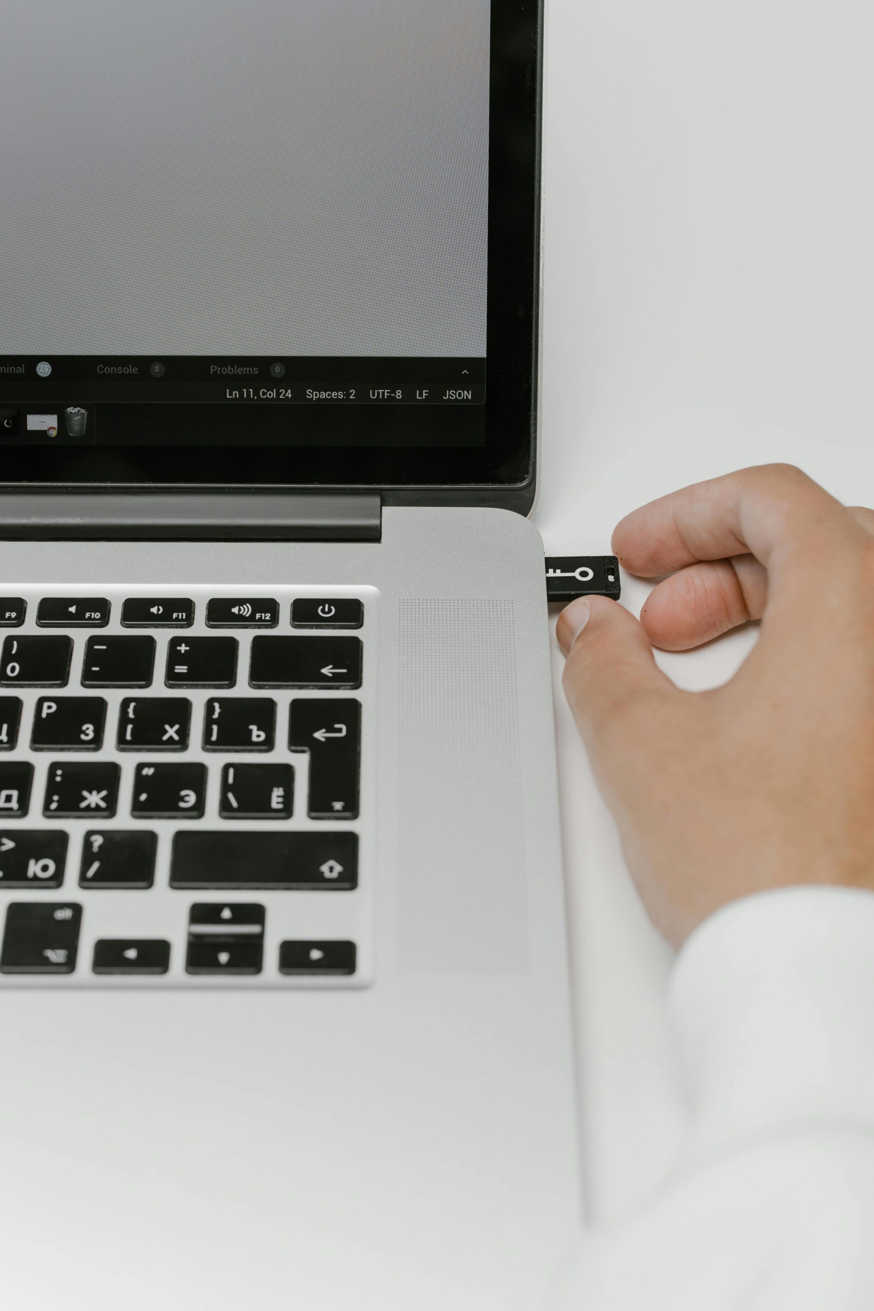 Close-up of a hand inserting a USB drive into a laptop port, symbolizing data transfer and technology use.