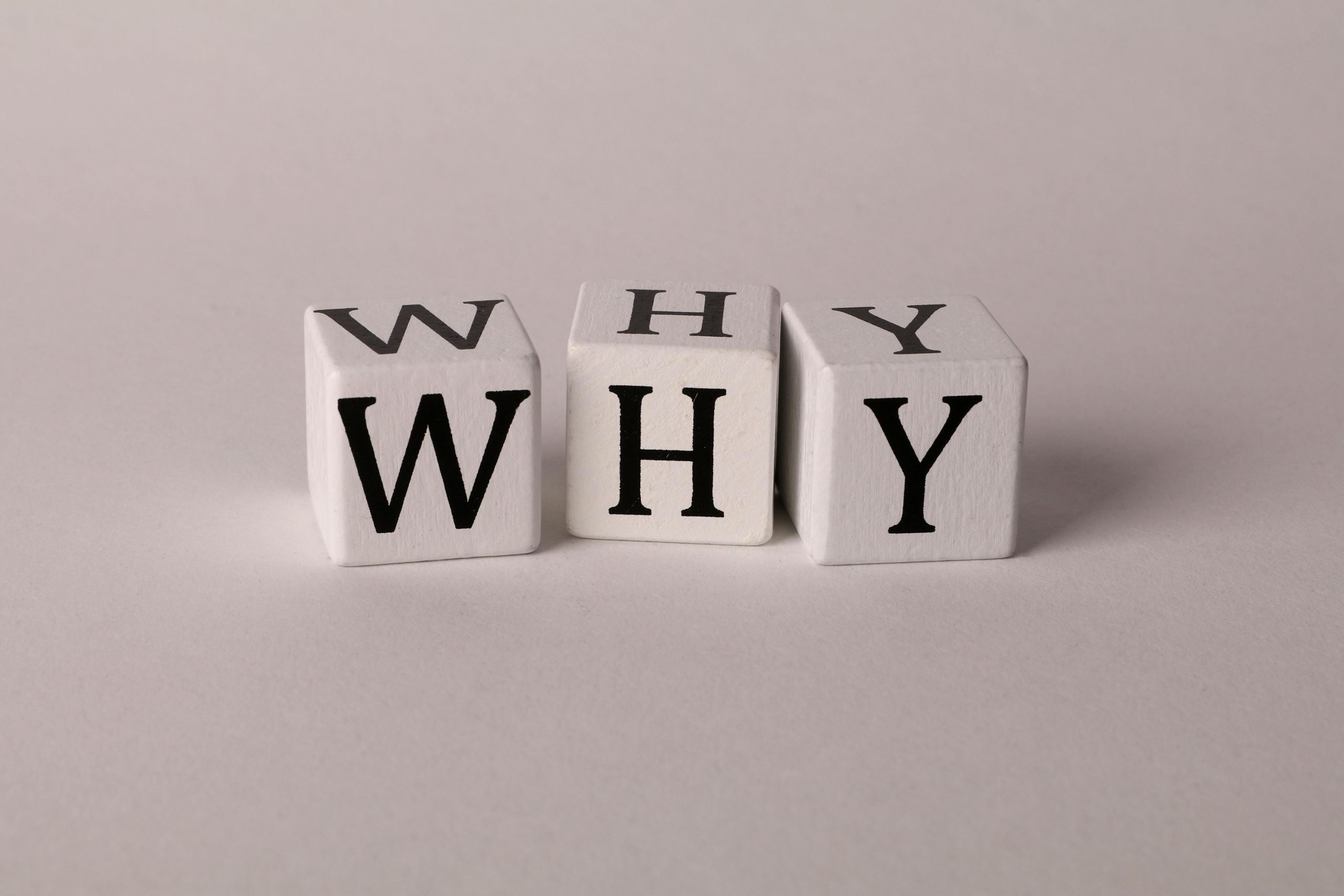 Close-up of lettered dice spelling 'WHY' on a neutral background, ideal for concepts of inquiry or curiosity.